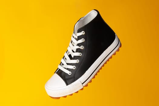New black and white canvas sneakers on yellow background