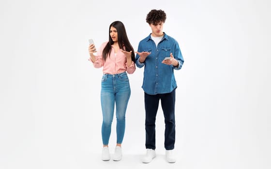 Displeased Students Couple Holding Smartphones Reading Negative Message, White Background