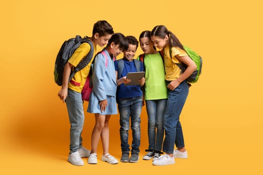 Smiling cute boy holding digital tablet, showing his classmates app