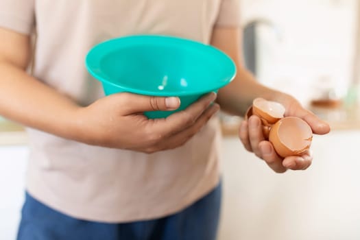 A woman breaks eggs into a deep bowl
