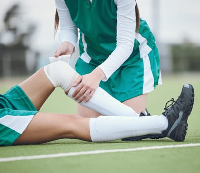 Athlete, knee injury and help on field, sports and accident in sportswear. Person, emergency and first aid for joint pain, bruise and inflammation to bandage, broken by fall and suffering in game
