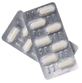 Oval white tablets in blister pack on a white isolated background, top view