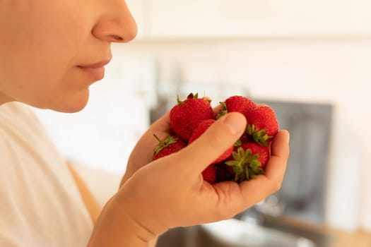 a woman holding a handful of strawberries