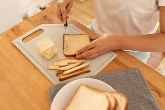 a woman sits in the kitchen cutting off crusts of bread