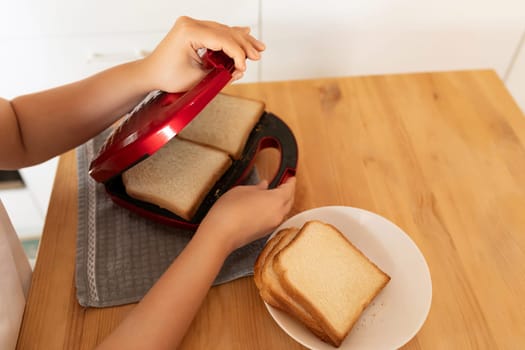 a woman puts slices of bread in the toaster