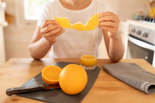 a bright fresh juicy orange in the hands of a woman in the kitchen