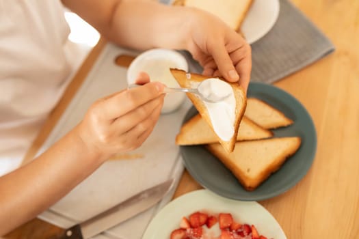 women's hands make a homemade strawberry sandwich