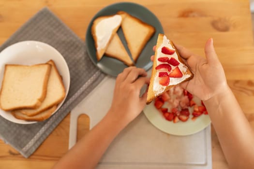 a woman makes breakfast, toast with sour cream and strawberries