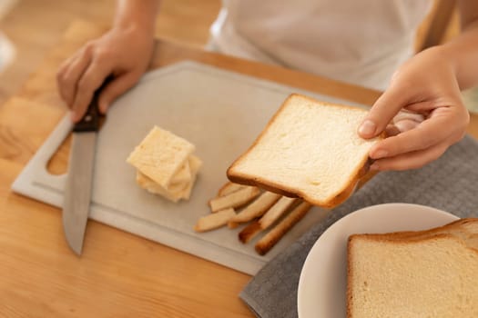 women's hands slicing bread on a board