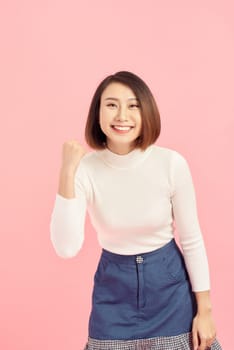 Asian businesswoman scream with joy and happiness, suprise feeling, winner expression, white sweater, pink background
