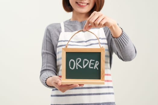 Portrait of smiling waitress showing chalkboard with order sign on white