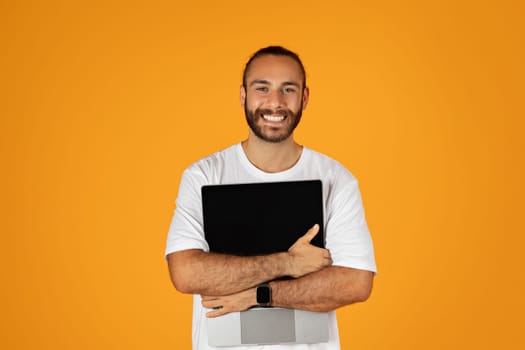 Happy adult european guy with beard in white t-shirt hugs laptop with blank screen, enjoy freelance