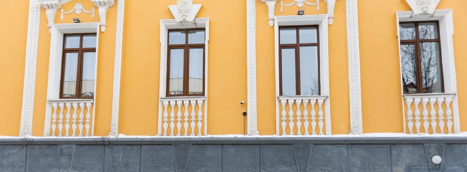 Elegant classical windows decorated with stucco ornaments on beige antique facades. Vintage classic architecture. Banner