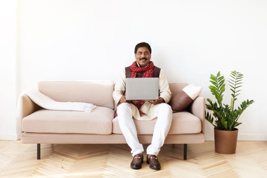 Happy indian man independent contractor using laptop at home