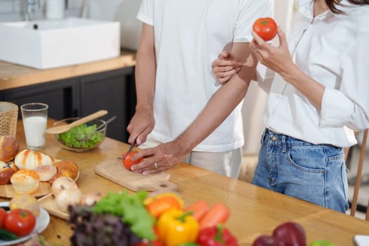 Couple cutting tomatoes for cooking or salad in home kitchen