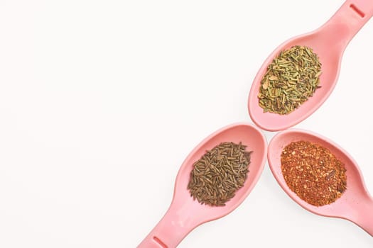 Pink spoons with different delicious fragrant spices for cooking,tea,drinks