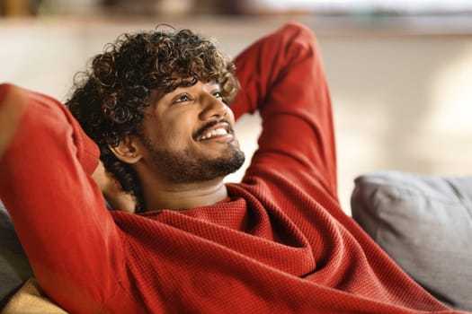 Relax Concept. Happy Young Indian Man Leaning Back On Sofa At Home