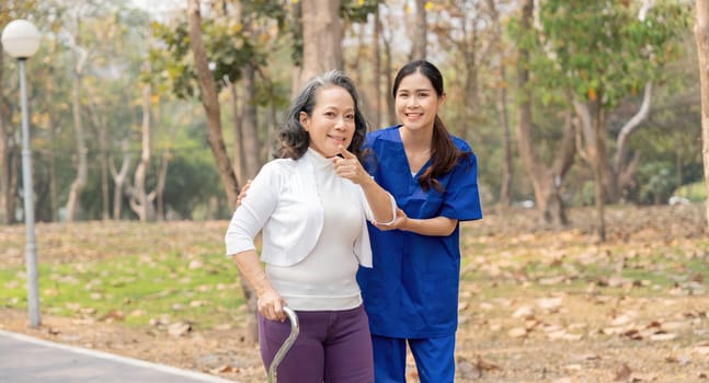 Nurse and senior in elderly care, support or walking with stick at park. Medical caregiver or therapist help patient or person with a disability in retirement or physiotherapy