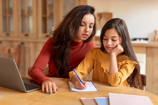 Mother and daughter working on school project together at home