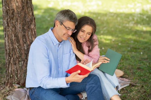 Romantic Mature Couple With Books Relaxing On Lawn In City Park