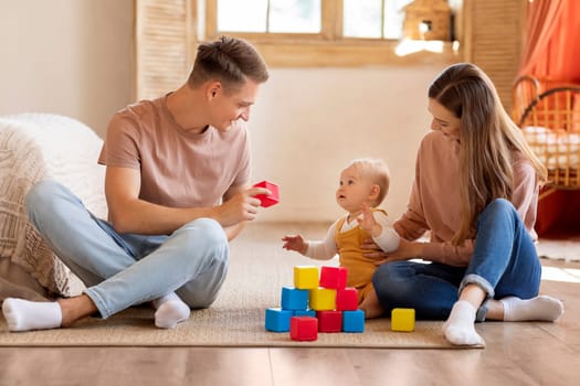 Caring Parents And Their Adorable Infant Son Playing With Toys At Home