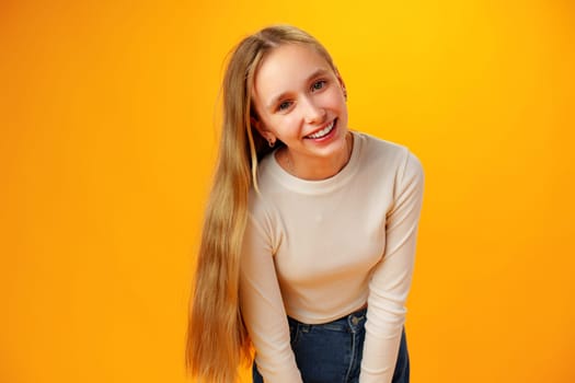 Photo of teen girl smiling portrait against yellow background in studio