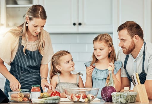 Happy family in kitchen, cooking together with children and teaching, learning and nutrition with parents. Mom, dad and girl kids help making healthy food in home with care, support and love at lunch