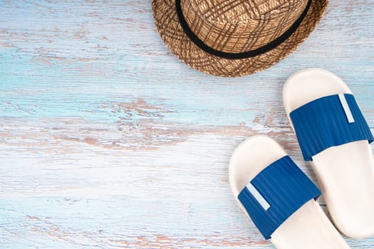 The Blue sandals and straw hat with copy-space on blue wooden background.