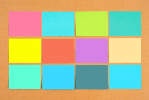 Multicolored of blank sticky notes on wooden board.