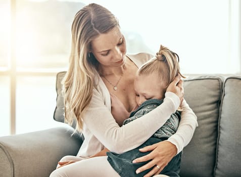 Hug, comfort and a mother and child on the sofa for support, crying and sad together. Family, house and a mom holding a tired or sick girl kid on a living room couch for care, love and console
