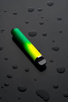 Electronic cigarette on black background with water drops