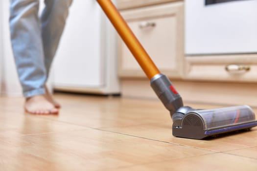 woman uses cordless vacuum cleaner to clean floor.