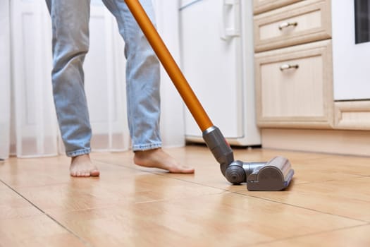 woman uses cordless vacuum cleaner to clean floor.