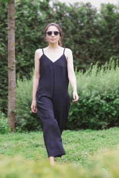 Beautiful young brunette woman, wearing black jumpsuit posing outdoors