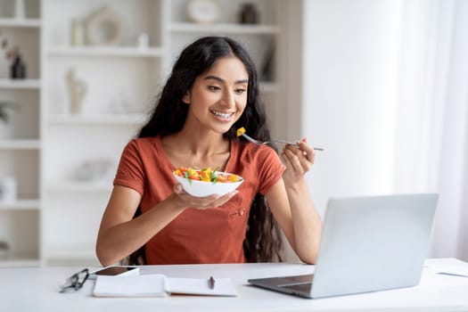 Cheerful millennial hindu woman have lunch break at home office