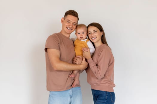 Portrait Of Happy Young Family Of Three With Adorable Infant Baby