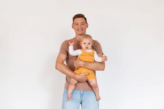 Parenting Concept. Portrait Of Young Dad With Cute Infant Baby In Hands