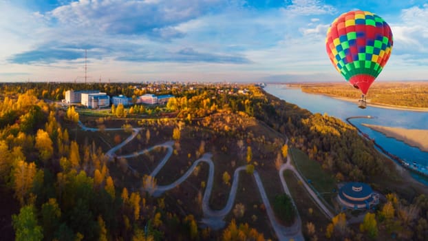 Hot air balloon above winding road in the city, drone shot. Barnaul, Siberia, Russia. Beauty autumn day