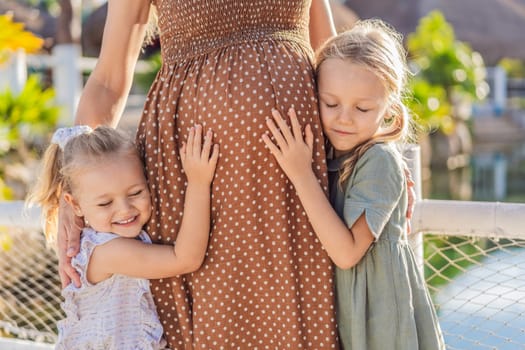 Sisters' love blooms as they tenderly embrace their mother's pregnant belly, sharing anticipation and affection for their soon-to-arrive sibling