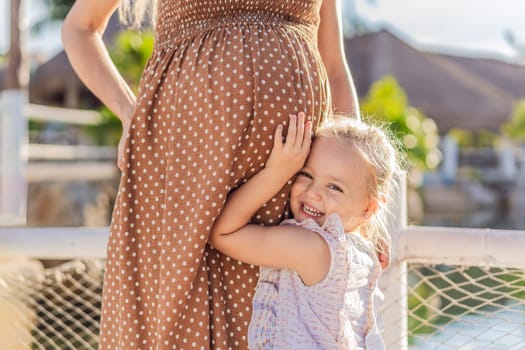 A heartwarming moment captured as a daughter lovingly embraces her mother's pregnant belly, sharing in the excitement and anticipation of a new family member