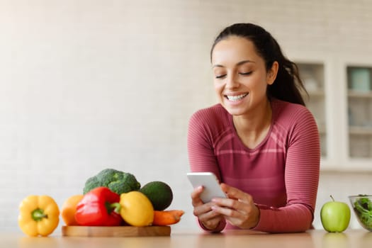 Fit Lady Using Weight Loss Application On Cellphone In Kitchen