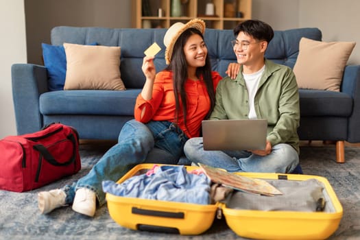 Korean couple using laptop booking vacation tour online at home