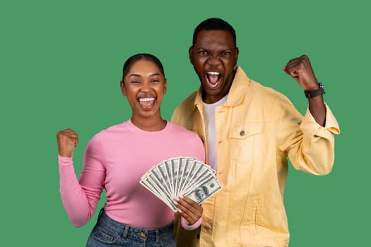 Overjoyed young African American couple holding bunch of money