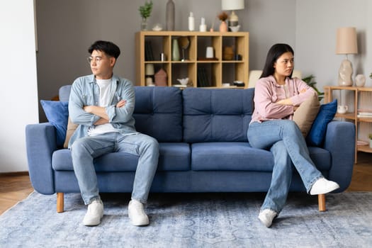 Korean couple sitting upset distancing after argument in living room