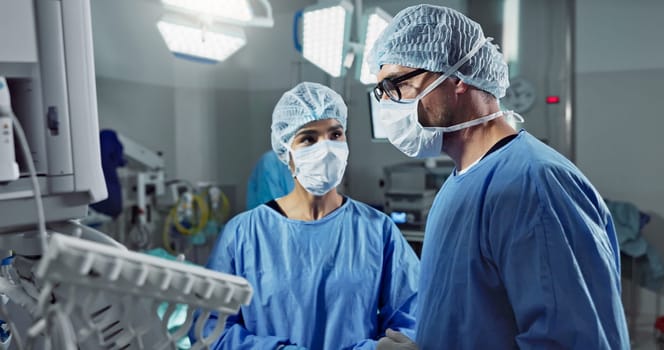 Medical team, people and doctor in operating room to talk, strategy and pointing at screen for surgery. Man, woman and scrubs in healthcare with equipment in theatre with monitor for xray of patient