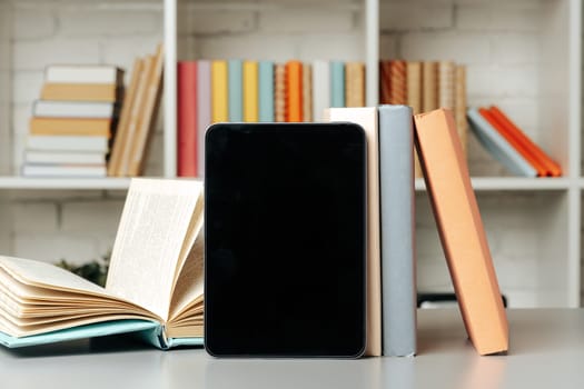 Digital tablet with stacked books in library