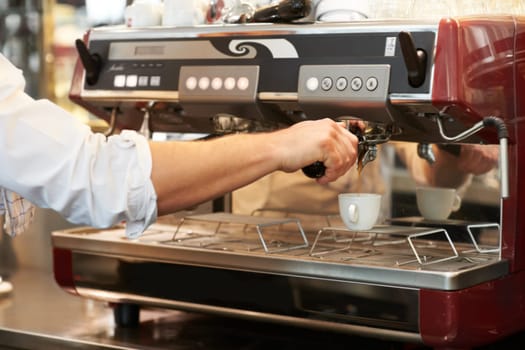 Coffee machine, closeup and man barista in a cafe making latte, cappuccino or espresso in a cup. Equipment, mug and zoom of male waiter or small business owner working on an order in a restaurant.