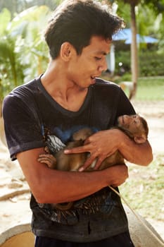 Zoo, animal and man with monkey in nature for care, conservation and wildlife rescue. Sanctuary, travel and happy person with macaque in environment, ecosystem and outdoors in Thailand for tourism