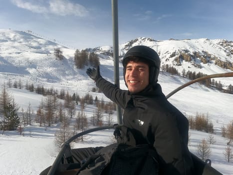 Portrait of handsome man in skiing suit sitting on chairlift