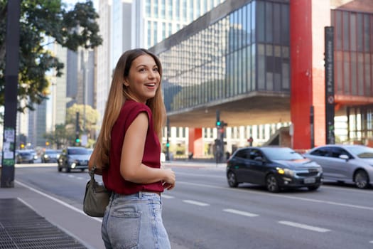 Brazilian young business woman waiting for a taxi or uber on Paulista Avenue, Sao Paulo, Brazil